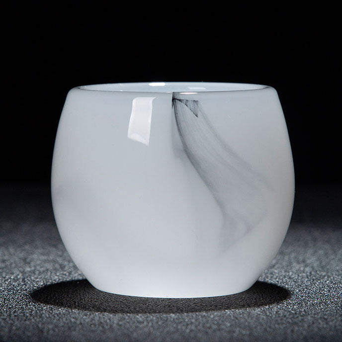A small translucent white glass cup with a rounded shape, photographed on a dark textured surface against a black background. A white label is attached near the rim, and a text banner appears along the bottom with Chinese characters and dimensions.
