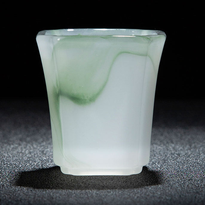 A translucent jade-like tumbler with a green marbled pattern, shown on a dark textured surface against a black background. A white and red text banner is at the bottom with Chinese dimensions and capacity details.