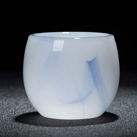 A small translucent white glass cup with soft blue marbled swirls, shown on a dark textured surface against a black background. A red and white text banner is visible at the bottom with product specifications in Chinese.