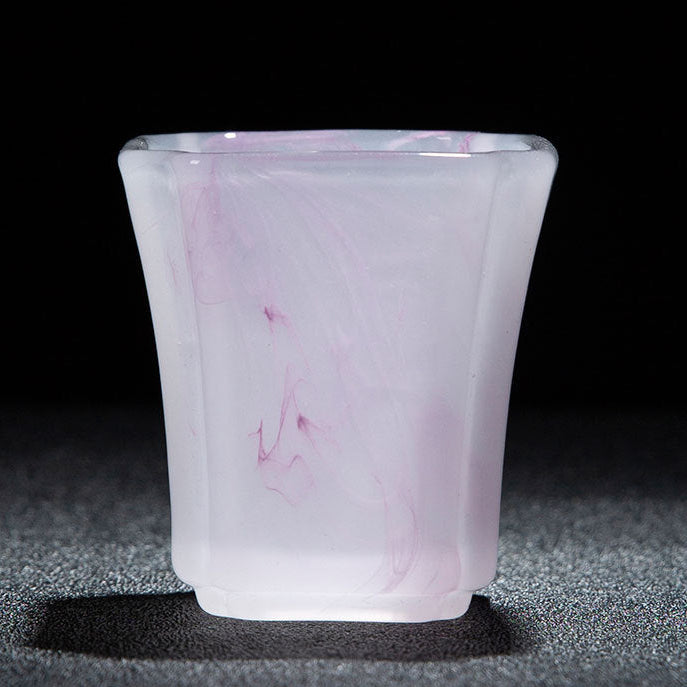 A translucent pale pink glass cup with subtle purple marbling, shown on a dark textured surface against a black background. A red text banner at the bottom displays dimensions and capacity in Chinese.