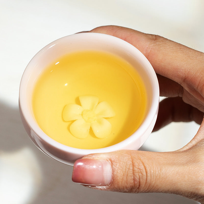 Close-up of a pink ceramic teacup with sculpted flower detail inside
